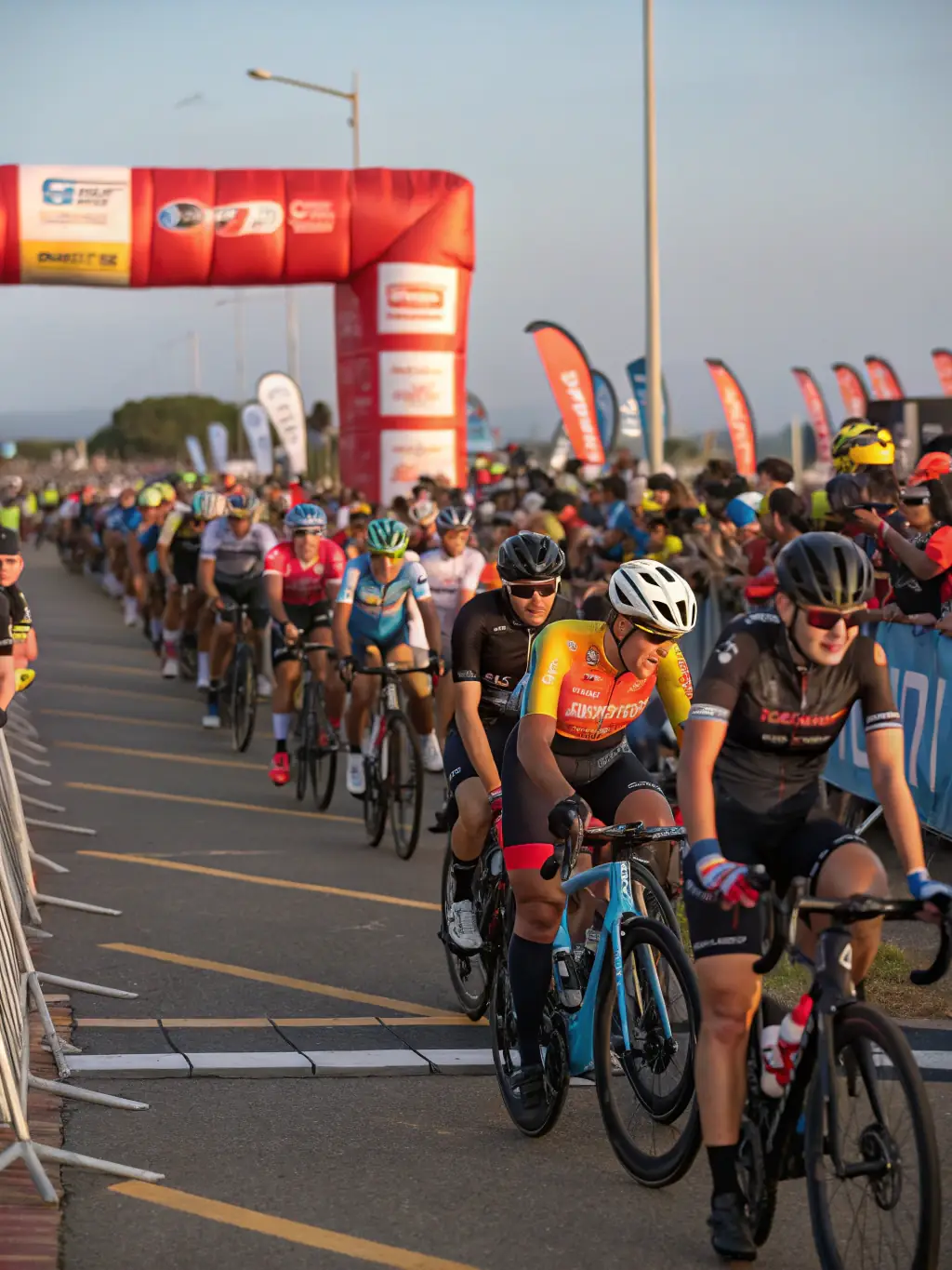 A photograph of cyclists gathered at the starting point of a charity ride, with registration tables and event banners visible in the background.